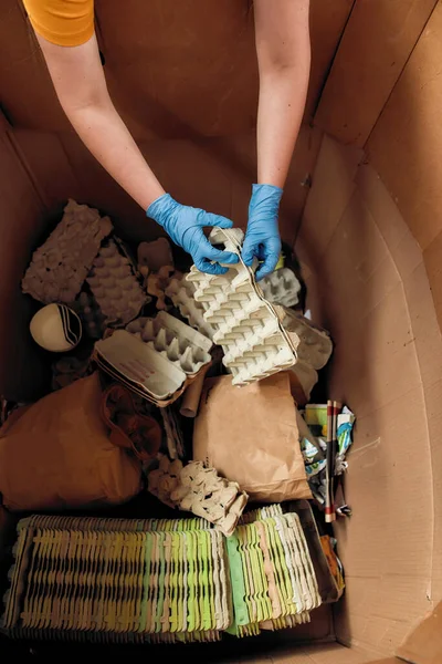 Ruce v rukavicích vkládají vajíčka do velké krabice — Stock fotografie