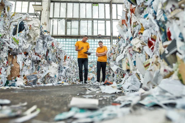 Homme parlant à une femme entre des piles de vieux papiers — Photo