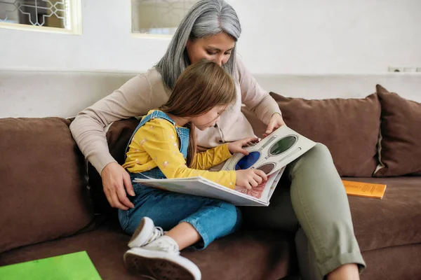 Bambina che legge libro con la nonna a casa — Foto Stock