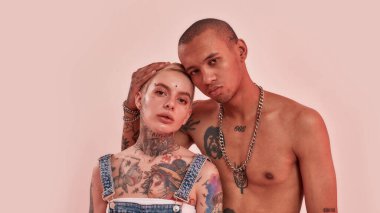 Çok kültürlü bir ilişki. Dövmeleri ve piercingleriyle birbirine yakın duran iki dövmeli çok kültürlü yetişkin.