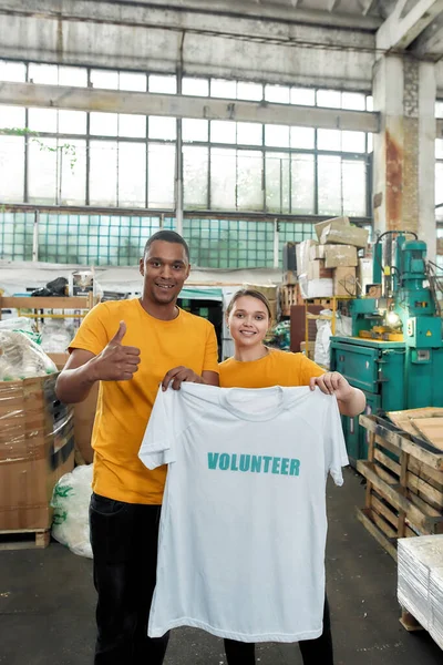 Kvinna håller t-shirt med tryckt volontär ord — Stockfoto
