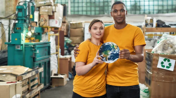 Young multiracial pair holding earth model — Stock Photo, Image