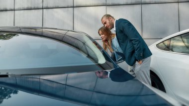 Lüks arabanın camına bakan mutlu genç eşler.