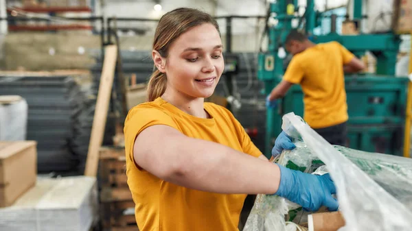 Meisje zet flessen in plastic zak op afvalstation — Stockfoto