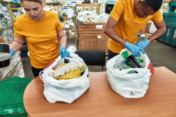 Jong meisje en man sorteren van afval uit plastic zakken — Stockfoto