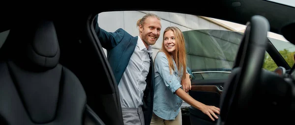 Glimlachend jong Kaukasisch paar op zoek naar auto interieur — Stockfoto