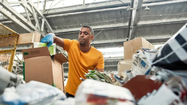 Young man packing boxes with waste paper — Stock Photo, Image