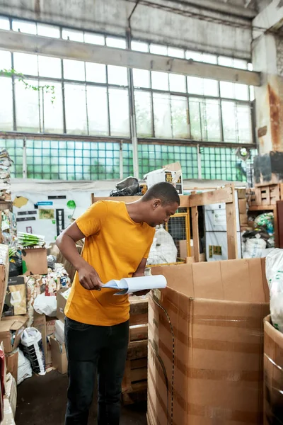 Afro-Amerikaanse man op zoek naar dozen op vuilnisstation — Stockfoto