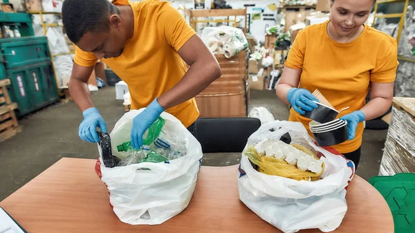 Jovem mulher e homem classificando lixo de sacos de plástico — Fotografia de Stock