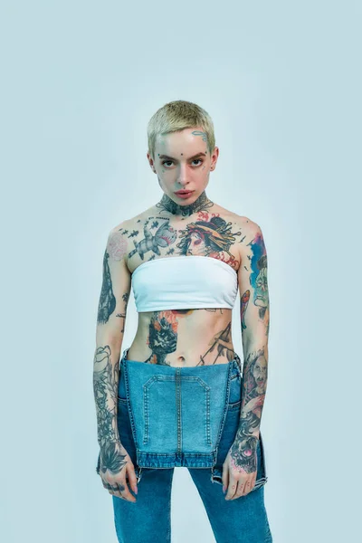 Look here. Portrait of half naked tattooed woman with short hair