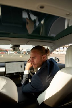 Yakışıklı genç işadamı arabanın camına bakıyor.