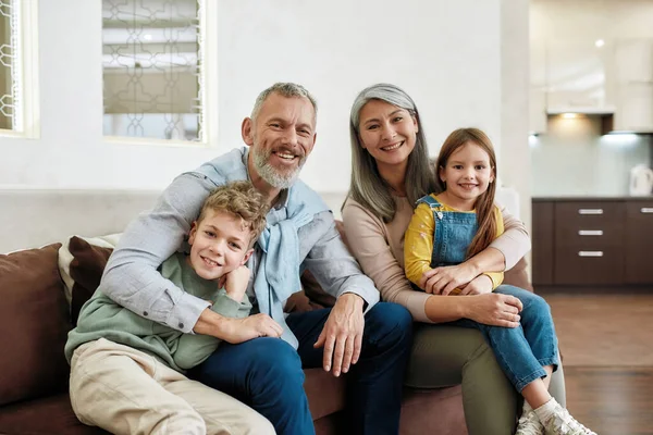 自宅で幸せな家族の時間を過ごすの肖像,リビングルームでソファの上でリラックス祖父母や孫,カメラで笑顔 — ストック写真