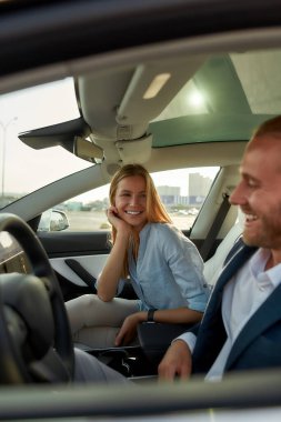 Arabaların ön koltuklarında oturan neşeli beyaz eşler.