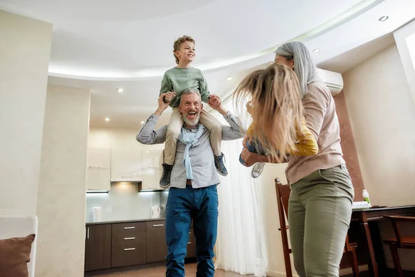 Wochenende mit der Familie. Zwei aufgeregte Jungen und Mädchen haben Spaß mit den Großeltern zu Hause, spielen und verbringen Zeit miteinander — Stockfoto