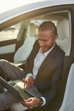 Genç Kafkasyalı işadamı laptopla arabada çalışıyor.