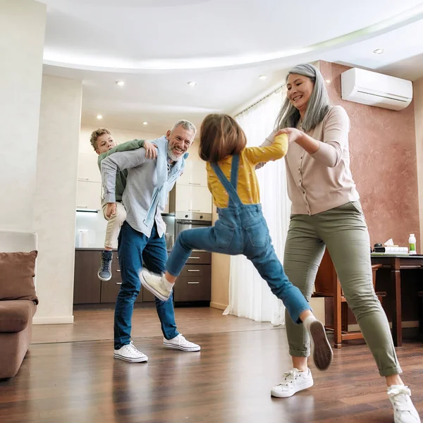 Gelukkig Kaukasisch gezin, grootouders en kleinkinderen hebben plezier, spelen en springen op de vloer in de woonkamer — Stockfoto