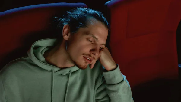 在电影院看电影时坐在椅子上睡着的年轻人的画像 — 图库照片