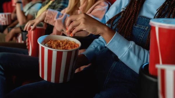 Nahaufnahme eines Mädchens, das Popcorn aus rotem mit weißem Korb nimmt, während es sich im Kino einen Film ansieht — Stockfoto