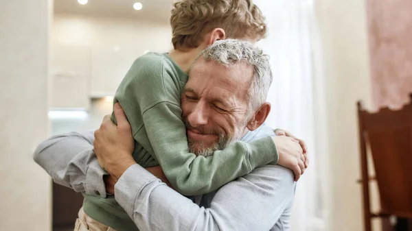 De liefde van opa. gelukkig grootvader omarmen zijn schattig kleine kleuterschool kleinzoon terwijl samen staan thuis — Stockfoto