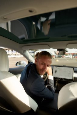 Neşeli genç işadamı geriye dönüp araba salonuna bakıyor.