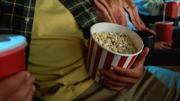 극장 강당에서 영화를 보면서 팝콘 바구니를 들고 있는 젊은 청년의 사진을 클로즈업 — 스톡 사진