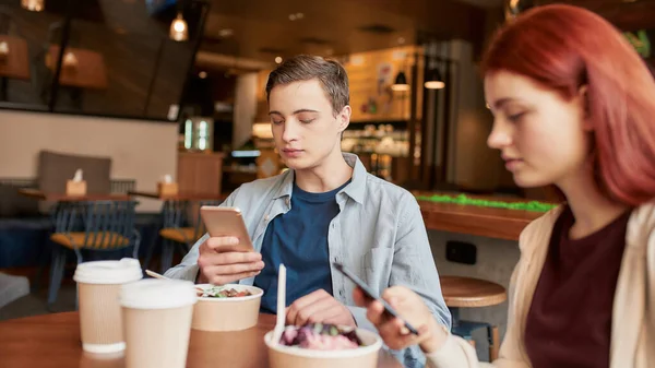 Πορτρέτο δύο εφήβων απορροφάται εντελώς από τη χρήση των τηλεφώνων τους, αγνοώντας ο ένας τον άλλον, ενώ κάθεται σε ένα καφέ μαζί σε μια ημέρα — Φωτογραφία Αρχείου