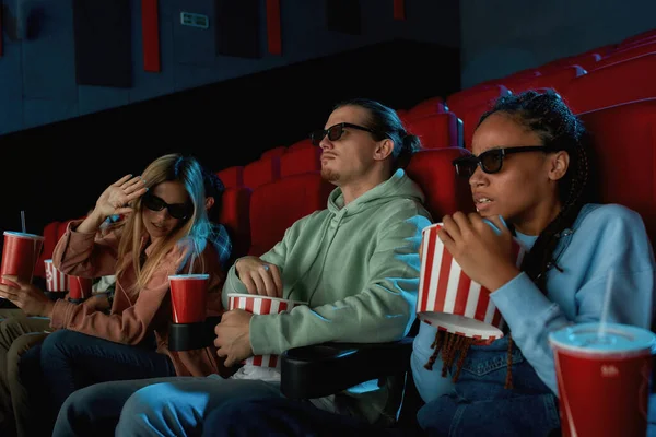 안경을 쓴 젊은 친구들이 극장 강당에서 함께 영화를 보면서 감동적으로 보이는 모습 — 스톡 사진
