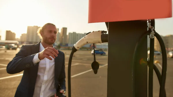 Knappe blanke zakenman neemt auto lader op laadstation — Stockfoto