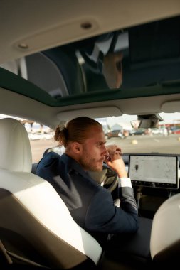 Yakışıklı beyaz adam arabanın camına bakıyor.