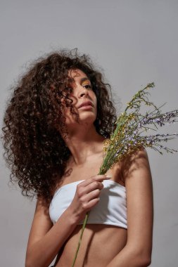 Omzunda buket taşıyan bir kadın yukarı bakıyor.