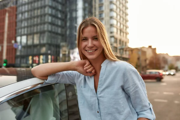 Portrait of happy young caucasian girl leaning on white car — Stock Photo, Image