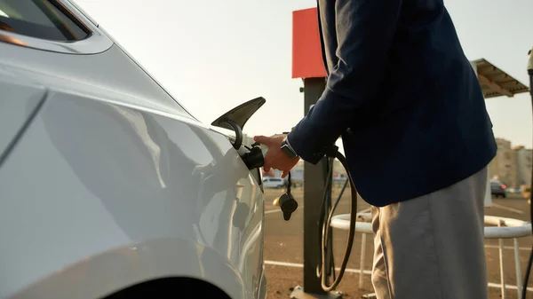 Jonge blanke man pluggen elektriciteit kabel in het voertuig — Stockfoto