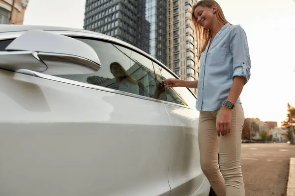 Gelukkig jong Kaukasisch meisje openen autoslot met behulp van kaart — Stockfoto