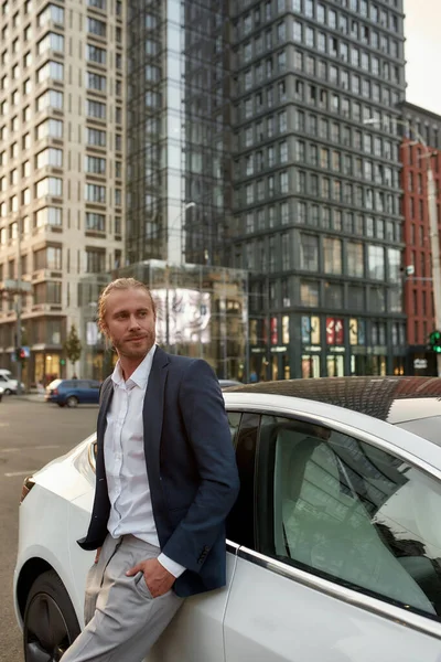 Glimlachende jonge zakenman in de buurt van een witte auto — Stockfoto