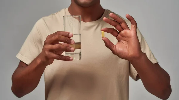 Pillola e acqua nelle mani del maschio afro-americano — Foto Stock