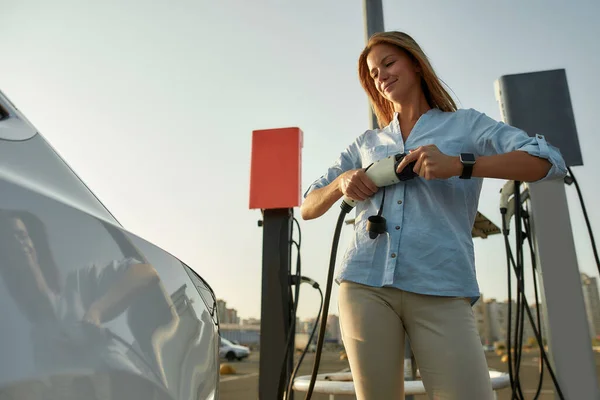 Vrouw stekker elektriciteit kabel in voertuig voor het opladen — Stockfoto