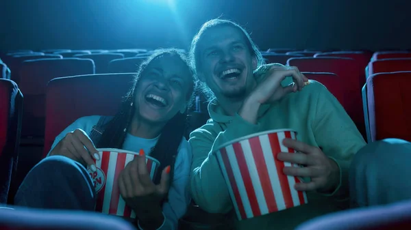 Лучшие друзья, молодой человек и женщина веселятся, сидят в кинотеатре, смотрят кино и едят попкорн — стоковое фото