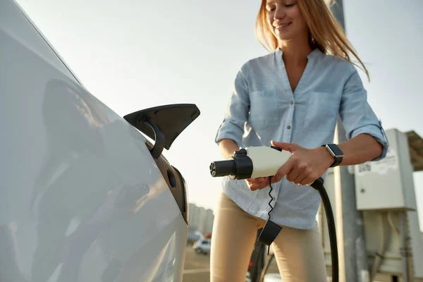 Girl plugging electricity cable in vehicle for charging — Stock Photo, Image