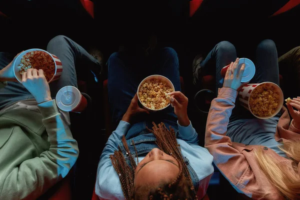 Vista dall'alto di amici che tengono cesti di popcorn mentre guardano film insieme al cinema — Foto Stock