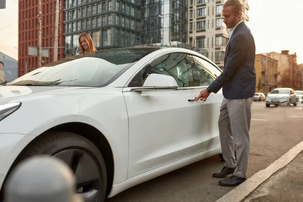 Knappe jonge zakenman krijgen in witte auto op straat — Stockfoto