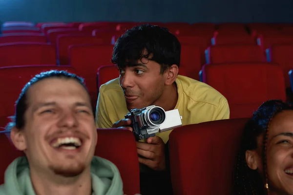 Portrait of young guy using his video camera for recording a pirated movie at the cinema — Stock Photo, Image