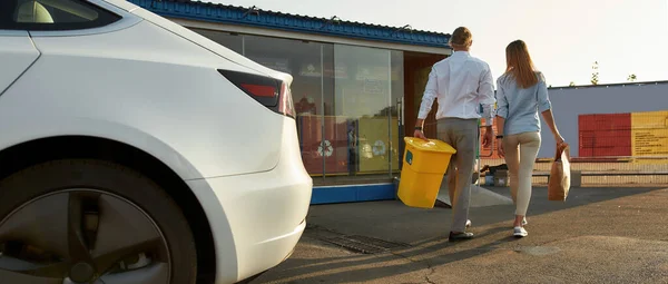 Jonge vrouw en man brengen tas en bak voor recycling — Stockfoto