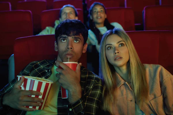 Porträt eines jungen Paares, attraktiver Mann und Frau, die sich wirklich für Filme interessieren, während sie zusammen im Kino bei Popcorn und Limo sitzen — Stockfoto