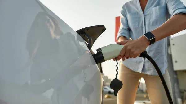 Vrouw stekker elektriciteit kabel in voertuig voor het opladen — Stockfoto