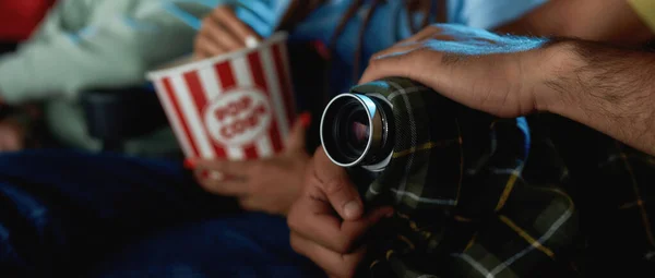 Close up tiro de mãos de um cara escondendo sua câmera de vídeo durante a gravação de um filme pirata no cinema — Fotografia de Stock