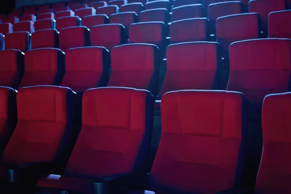 Close up shot of interior of cinema auditorium with lines of red chairs in front of a big screen