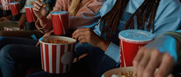 Close up of girl holding red with white basket of popcorn while watching movie at the cinema — Stock Photo, Image