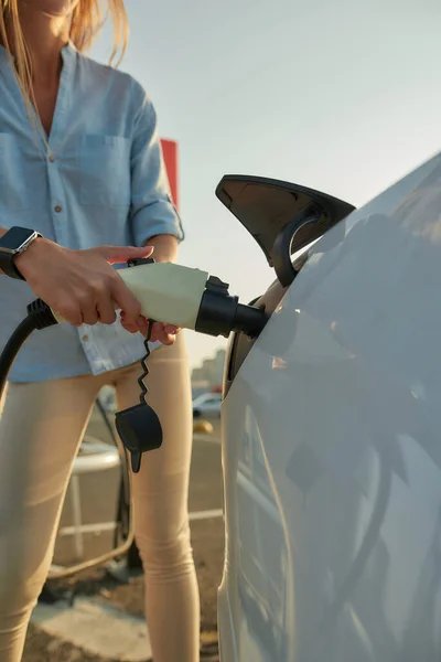 Vrouw stekker elektriciteit kabel in voertuig voor het opladen — Stockfoto