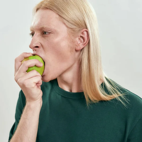 Portrait of young caucasian man biting green juicy apple — Stock Photo, Image