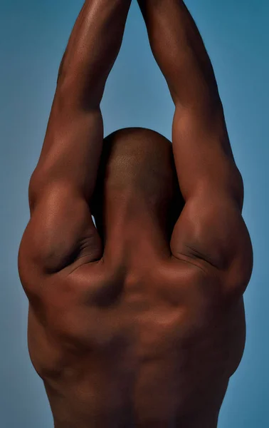 Afro-American athlete with raised arms tensing the back muscles
